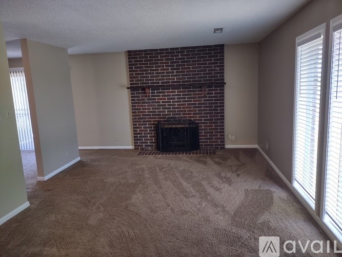 A living room with a fireplace and carpeted floor.