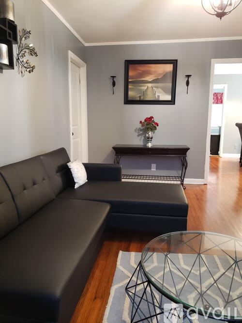 A living room with a grey couch and a glass coffee table.
