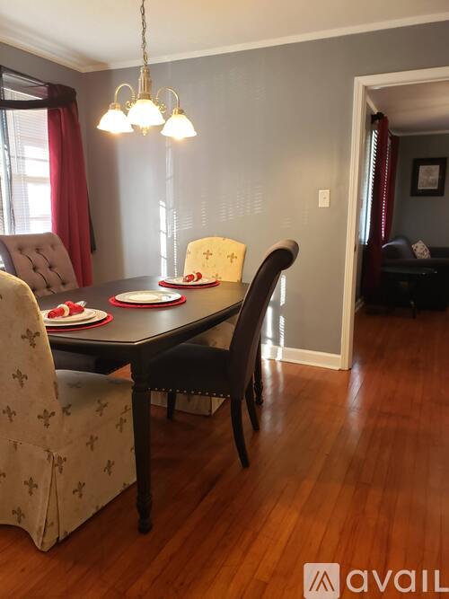 A dining room with a table set for two and a chandelier hanging from the ceiling.