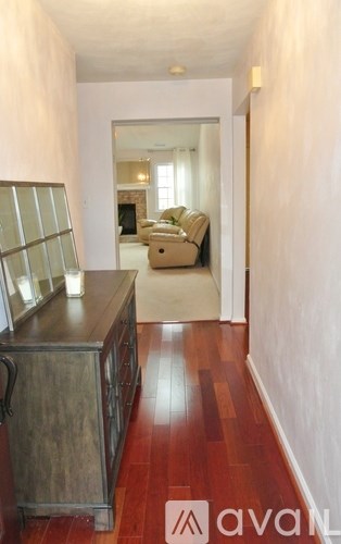 A hallway with wood floors and a kitchen area with a wooden island.