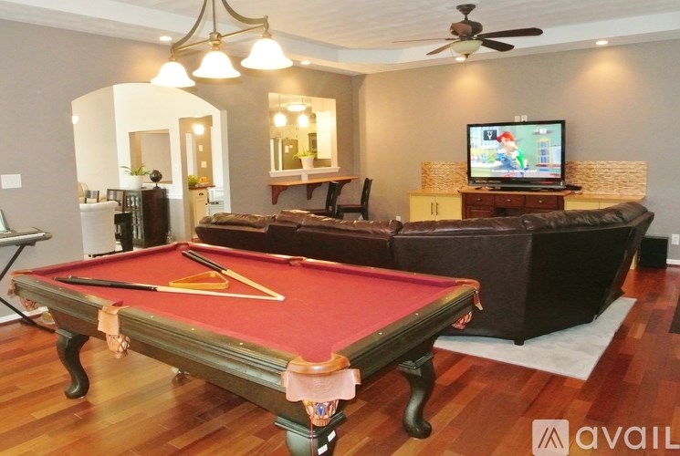 A pool table is in the middle of a room with a couch and a television.