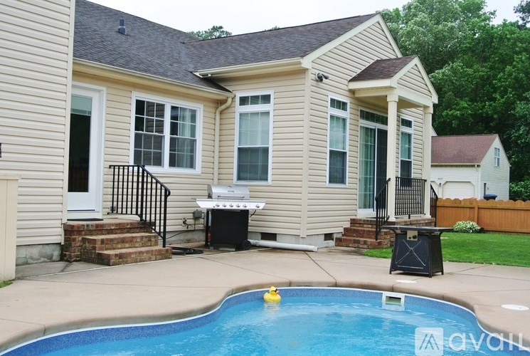 A pool in front of a house with a grill and a hot tub.