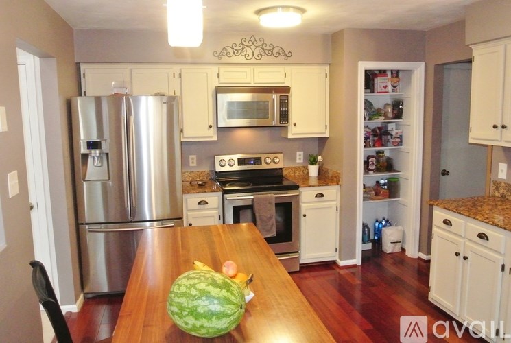 A kitchen with a wooden table and a watermelon on it.