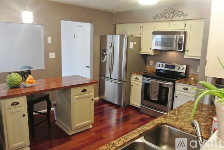 A kitchen with a refrigerator, microwave, oven, and sink.