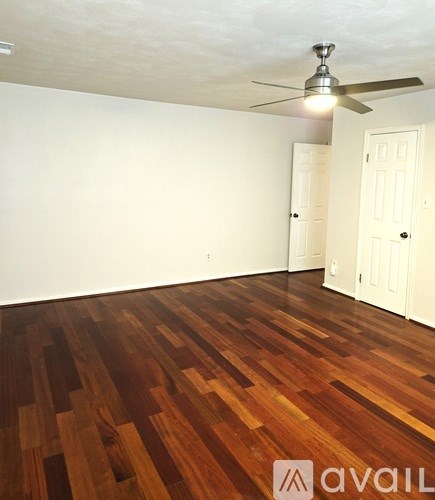 A living room with a brown leather couch and a television on a wooden stand.