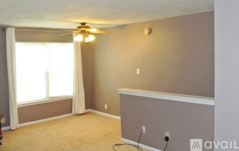 A room with a ceiling fan and a window with curtains.