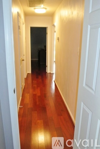 A hallway with wooden floors and white walls.