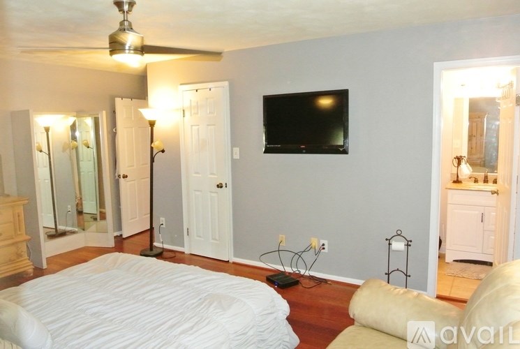 A bedroom with a bed, a couch, a television, and a mirror.