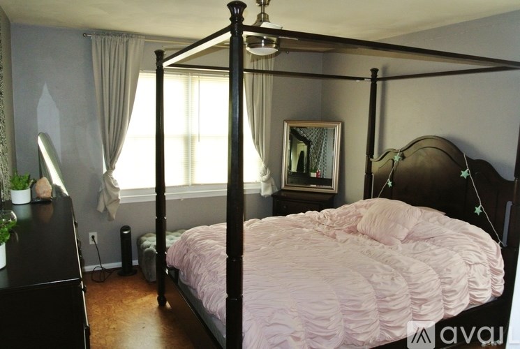 A bedroom with a four poster bed and a pink comforter.