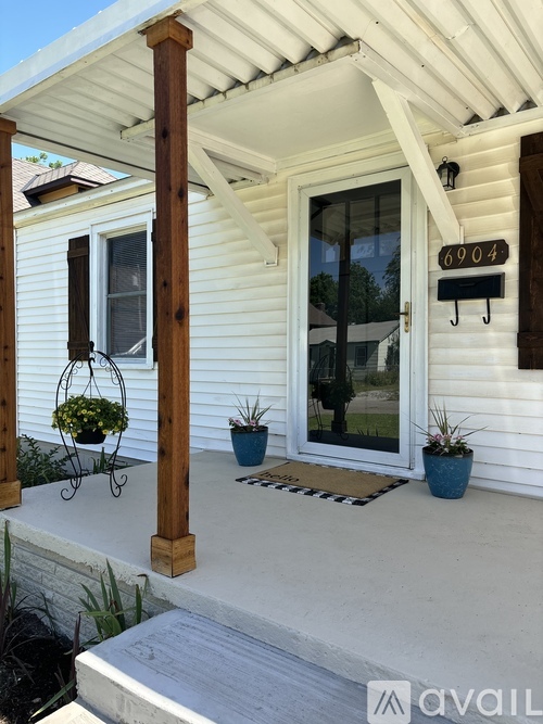 A white house with a porch and a mailbox that says 6904.