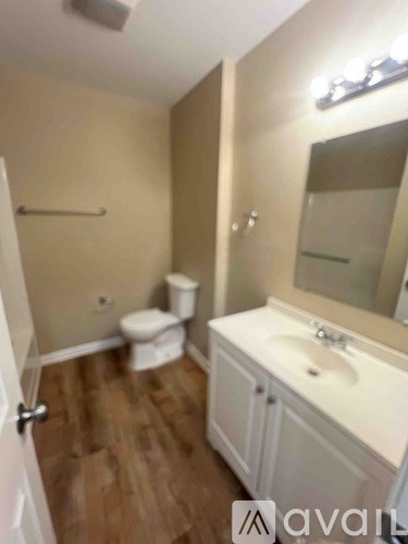 A bathroom with a toilet, sink, and mirror.