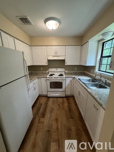 A kitchen with white appliances and wooden floors.