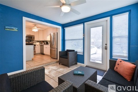 A living room with a black couch and a fan.