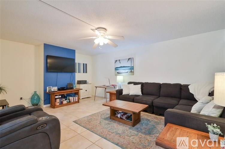 A living room with a black couch, a wooden coffee table, and a blue accent wall.