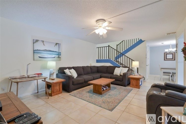 A living room with a couch, coffee table, and a staircase.