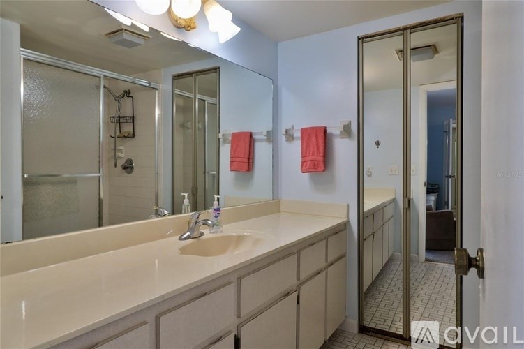 A bathroom with a sink, mirror, and shower.