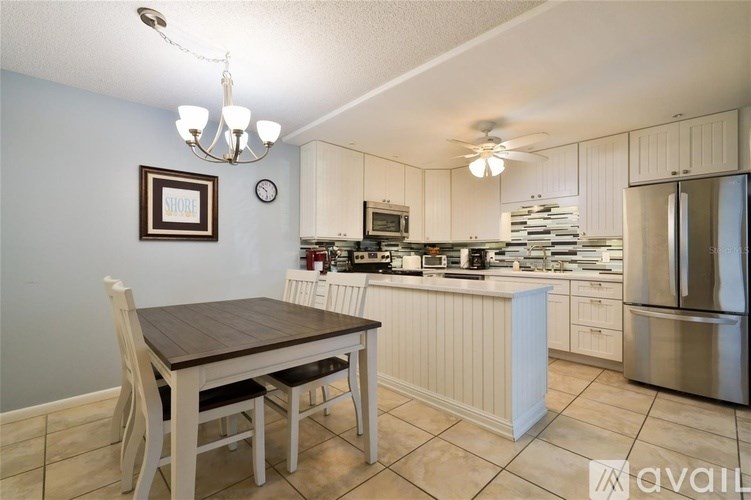 A kitchen with a table and chairs in the foreground and a fridge, microwave, and oven in the background.