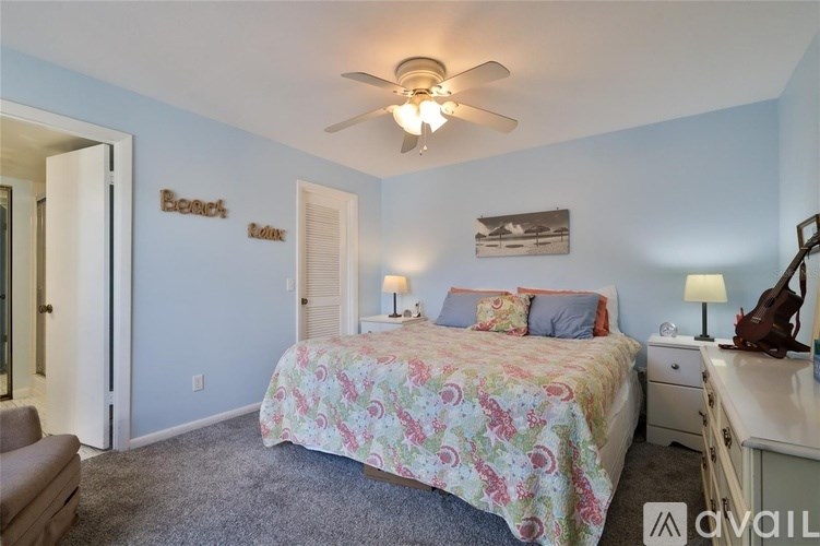 A bedroom with a bed, dresser, and ceiling fan.