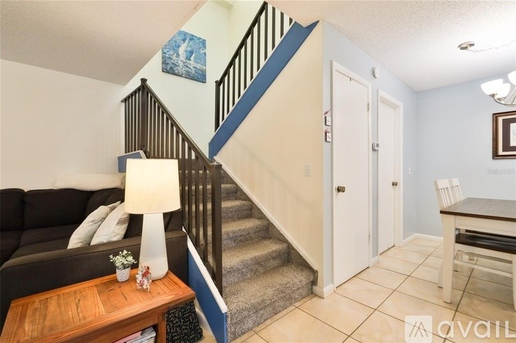 A living room with a couch, a coffee table, and a staircase.