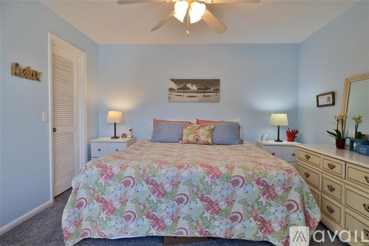 A bedroom with a floral bedspread and a ceiling fan.