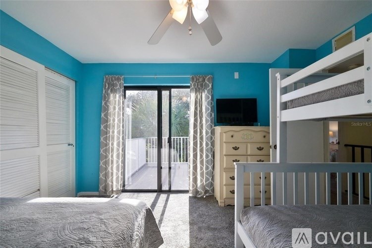A bedroom with a bed, dresser, and bunk bed with a sliding glass door leading to a balcony.