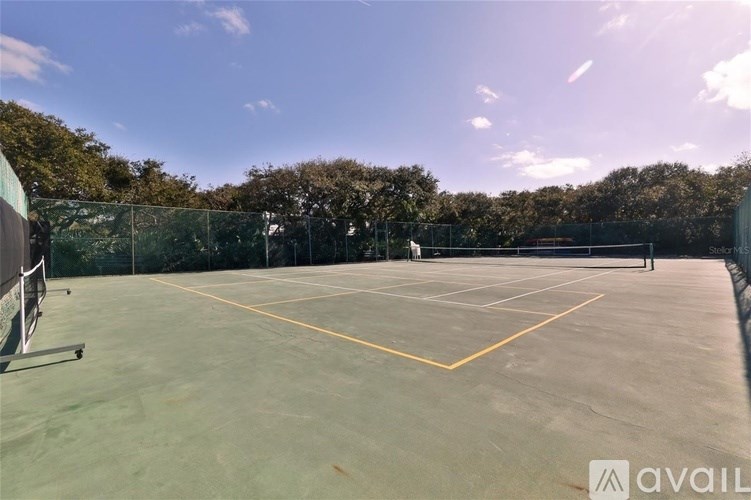 A tennis court with a net and trees in the background.