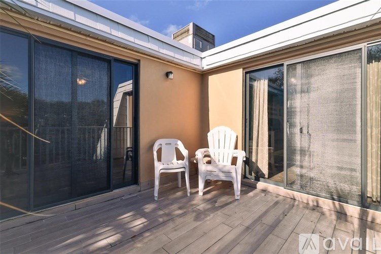 Two white chairs are on a wooden deck.
