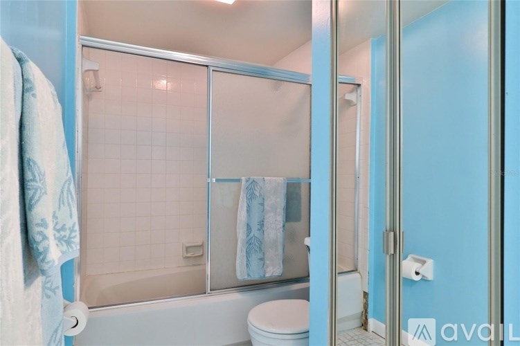 A bathroom with a toilet, a shower with a glass door, and a towel hanging on the door.