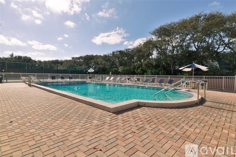A large outdoor swimming pool surrounded by a brick patio.