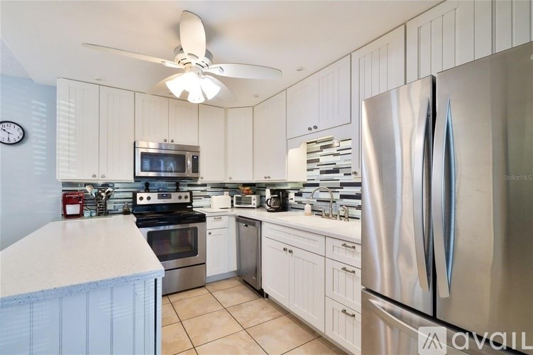 A modern kitchen with a stainless steel refrigerator and white cabinets.