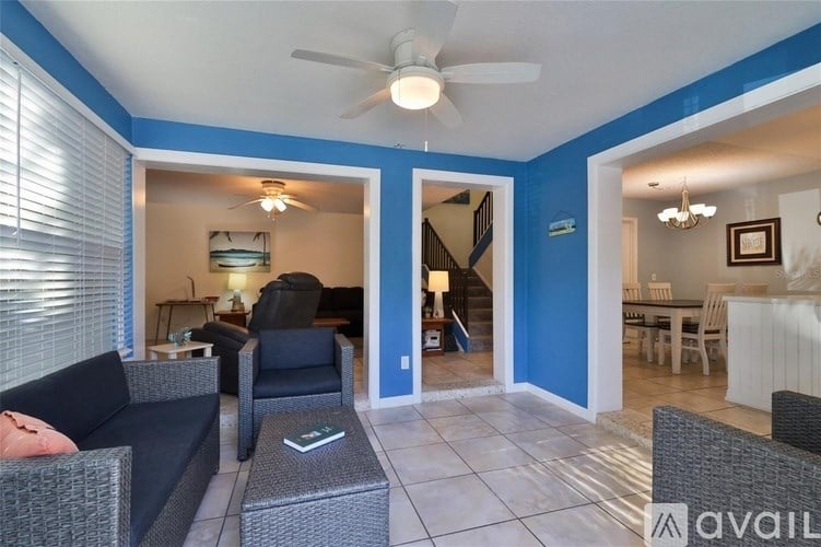 A living room with a couch, chairs, and a ceiling fan.