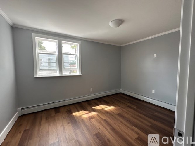 A room with wooden floors and a window letting in sunlight.