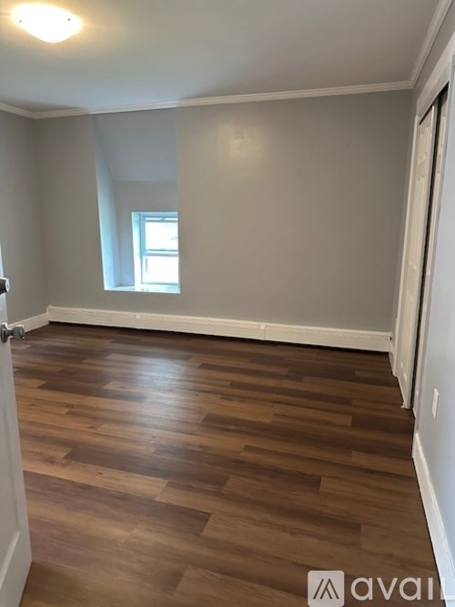 A room with wooden flooring and a window.