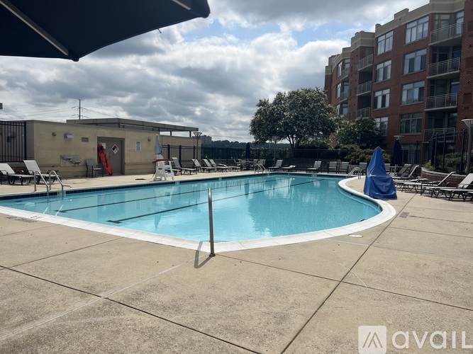 A large outdoor swimming pool with a blue umbrella and lounge chairs.