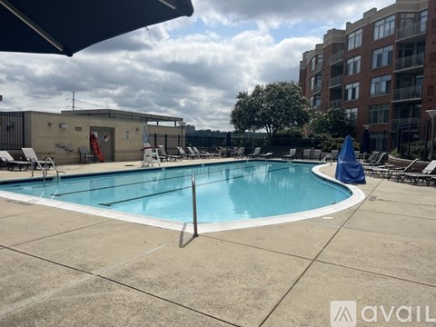 A large outdoor swimming pool with a blue umbrella and lounge chairs.
