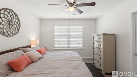 A bedroom with a bed, dresser, and ceiling fan.