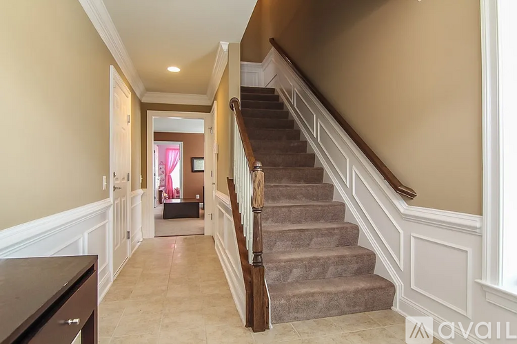A staircase with a wooden banister and beige carpeted steps.