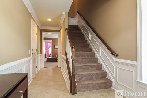 A staircase with a wooden banister and beige carpeted steps.