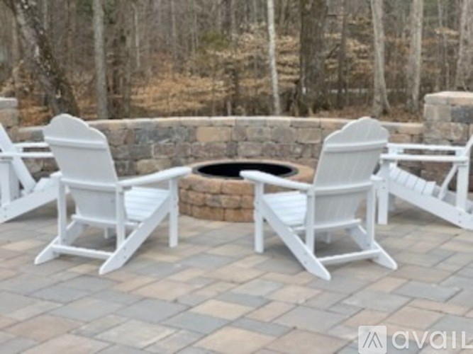 Two white chairs are placed on a patio.