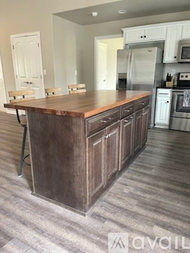A kitchen with a wooden island and stainless steel appliances.