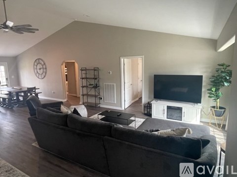 A living room with a grey couch and a television on a white stand.