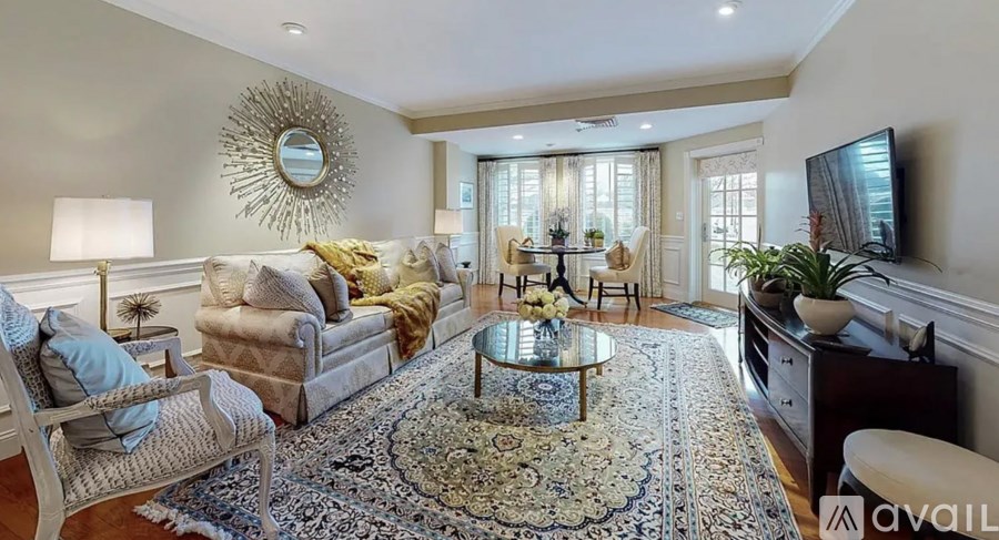 A living room with a rug, a sofa, a chair, a coffee table, a mirror, and a television.