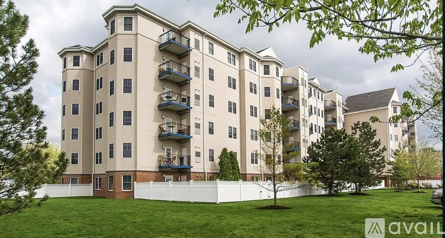 Apartment building with balconies and a white fence in front.