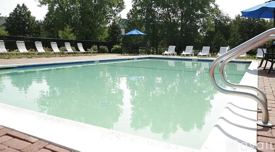 A pool with a metal ladder and white chairs around it.