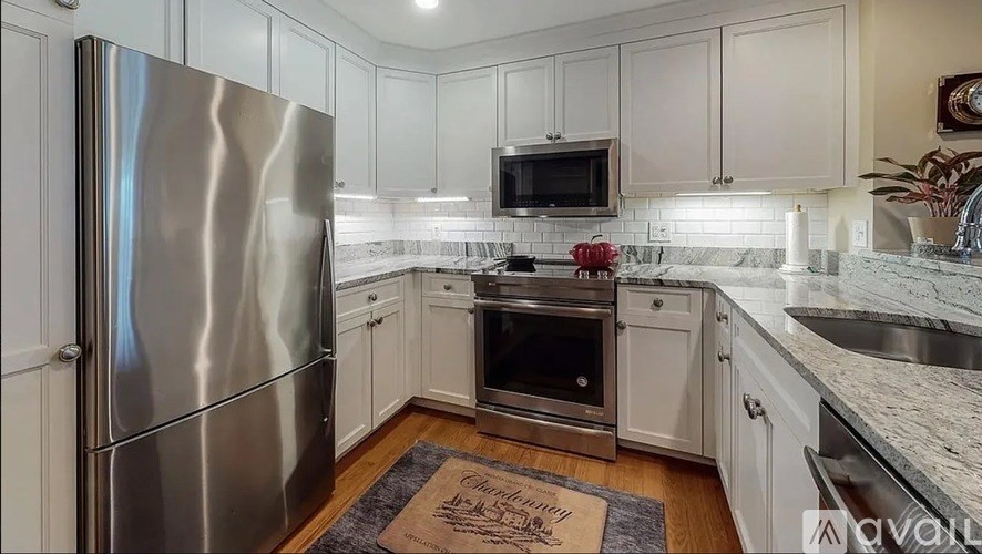 A kitchen with a stainless steel refrigerator and white cabinets.