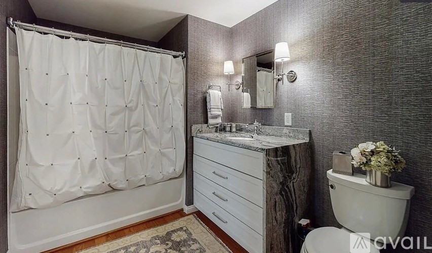A bathroom with a white shower curtain, a white toilet, and a wooden vanity.