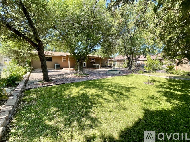 A well-maintained lawn with a house and trees in the background.