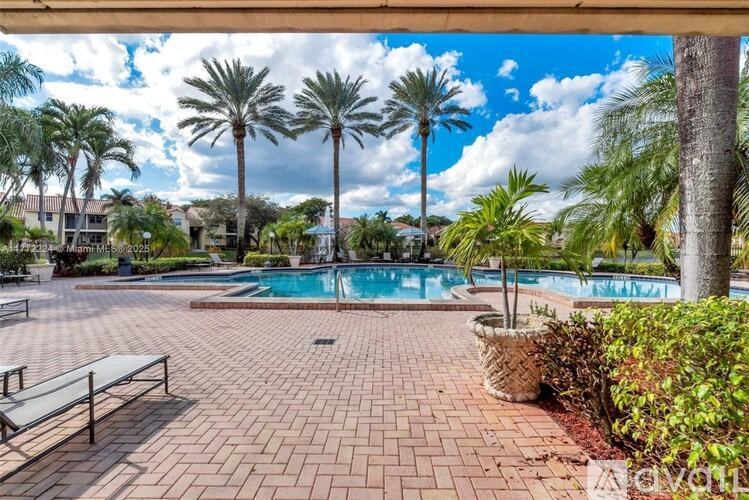 A pool surrounded by palm trees and a bench.