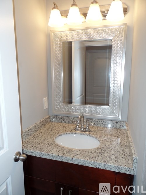 A bathroom with a granite counter top and a large mirror above the sink.