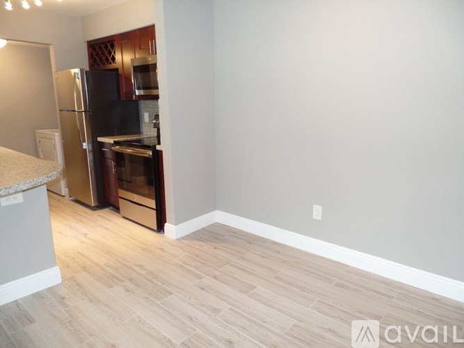 A kitchen with a black fridge and wooden cabinets.
